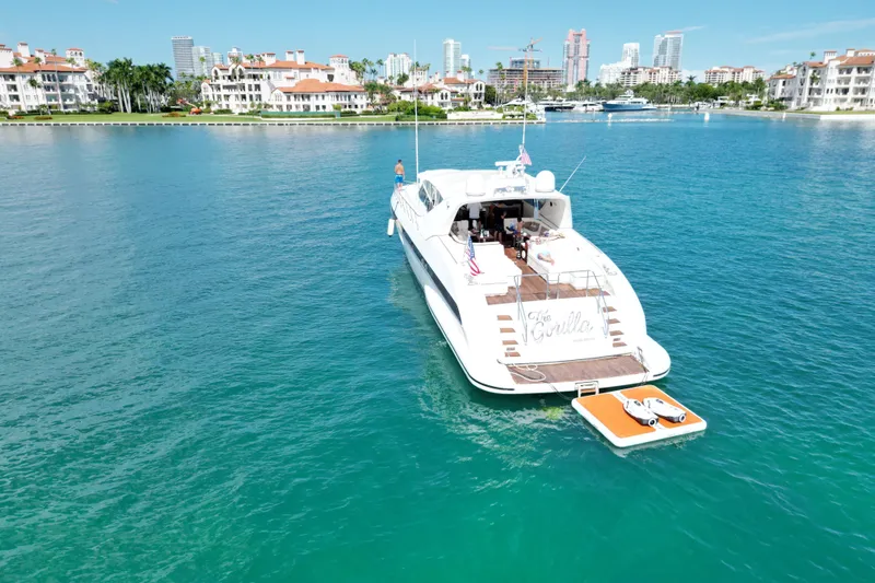 Slide: The Image of Luxurious 1999 Mangusta 80 yacht on serene blue waters near coastal residences. - 9