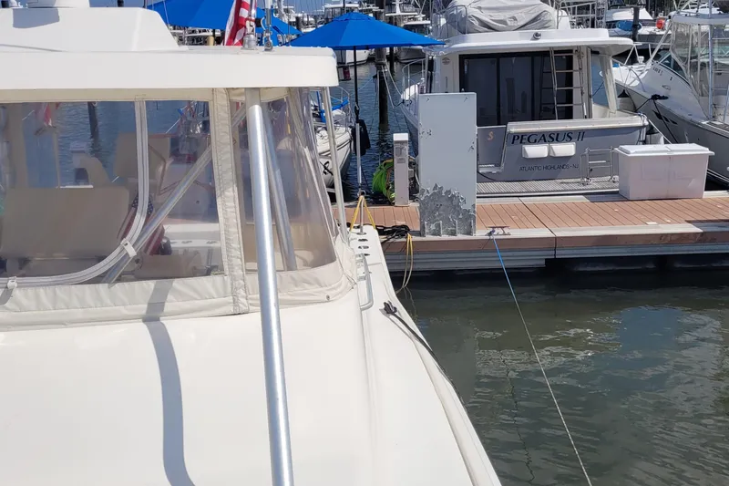 Slide: The Image of 1992 Luhrs 380 Open yacht docked at marina with nearby boats and blue umbrellas. - 19