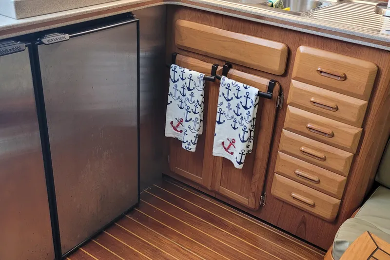 Slide: The Image of 1992 Luhrs 380 Open yacht kitchen with wooden cabinets, anchor-themed towels, and stainless steel fridge. - 36