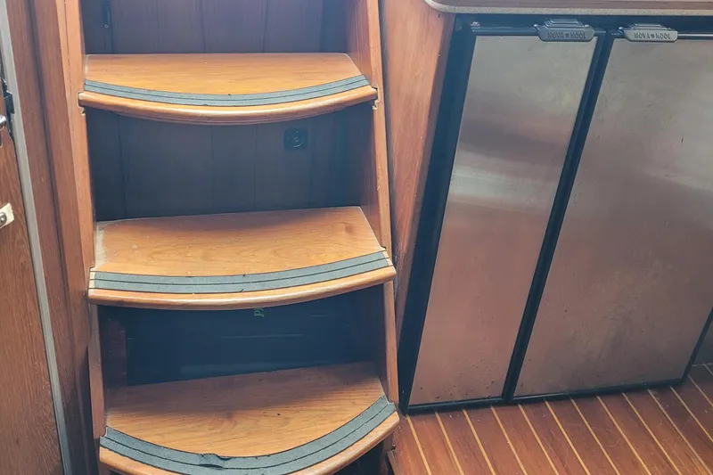 Slide: The Image of Wooden steps and stainless steel appliances in a 1992 Luhrs 380 Open boat interior. - 38