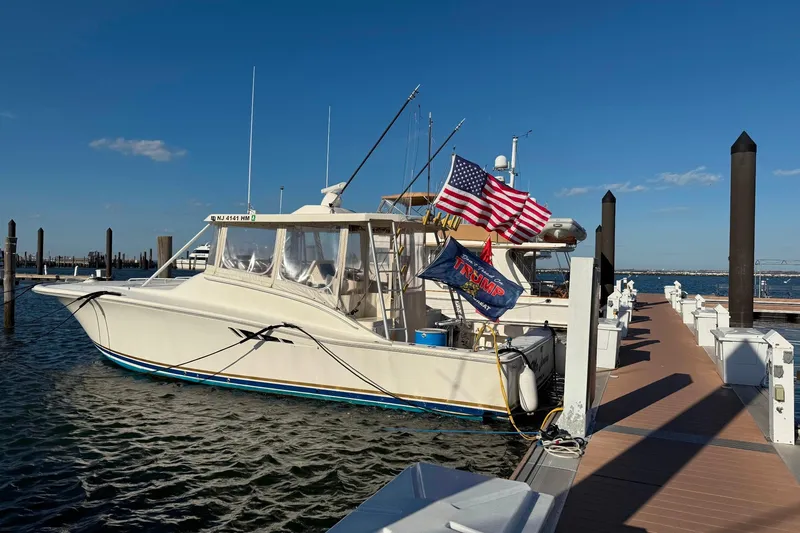 Slide: The Image of 1992 Luhrs 380 Open boat docked, displaying American and political flags, under clear blue sky. - 58