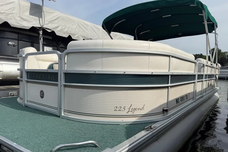 Slide: The Image of 2007 Premier 22 pontoon boat with green canopy and white seating, docked at marina. - 1