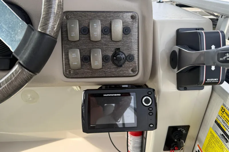 Slide: The Image of Boat dashboard with steering wheel, control panel, Humminbird Helix 5, and Suzuki remote control. Premier 22, 2007. - 13