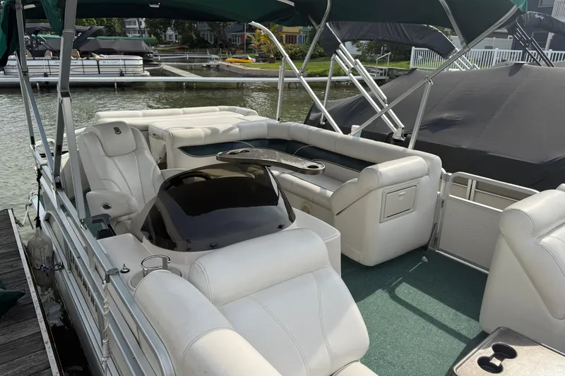 Slide: The Image of Luxurious 2007 Premier 22 pontoon boat with white seating and green carpet docked by the water. - 26