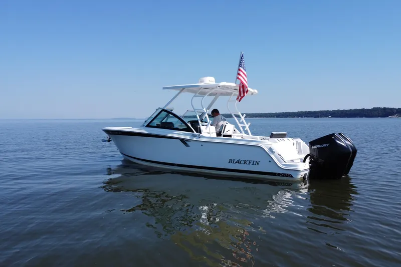 Slide: The Image of 2021 Blackfin 252 DC boat on calm water with American flag and Mercury engine. - 13