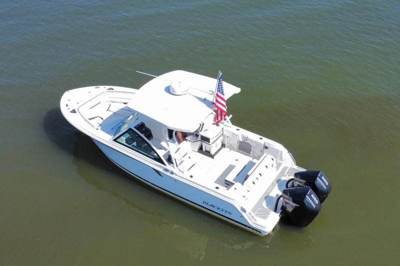 Slide: The Image of 2021 Blackfin 252 DC boat with dual engines, American flag, on calm water. - 16