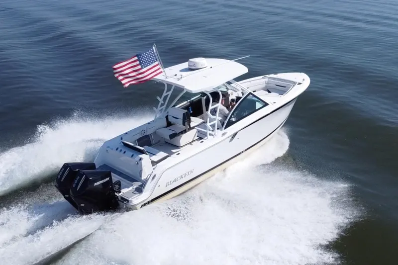 Slide: The Image of 2021 Blackfin 252 DC boat cruising with American flag on open water. - 4