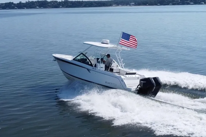 Slide: The Image of 2021 Blackfin 252 DC boat cruising on water with American flag. - 9