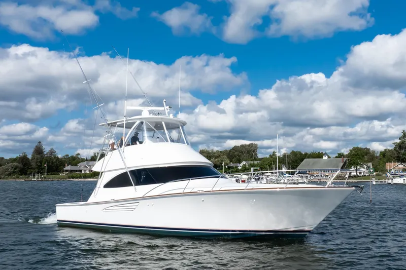 Slide: The Image of 2025 Viking 48 Convertible yacht cruising on a scenic waterway under a partly cloudy sky. - 2