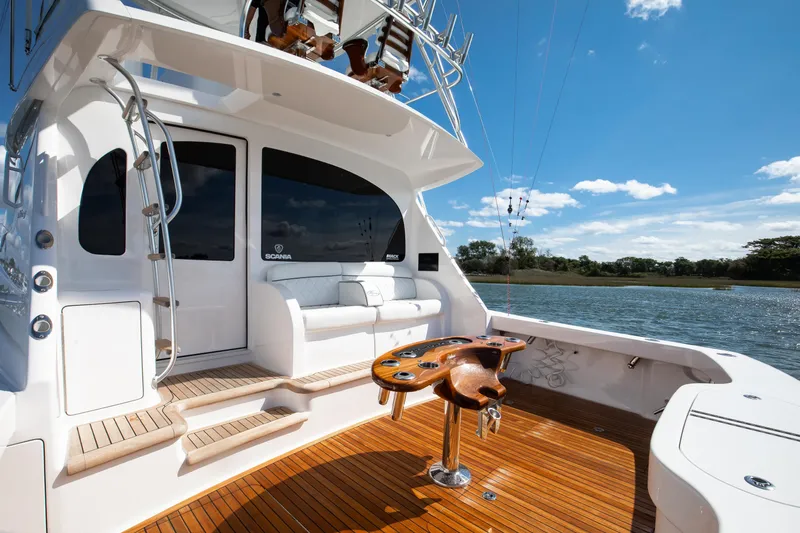 Slide: The Image of 2025 Viking 48 Convertible yacht deck with seating, fishing rod holders, and scenic water view. - 39