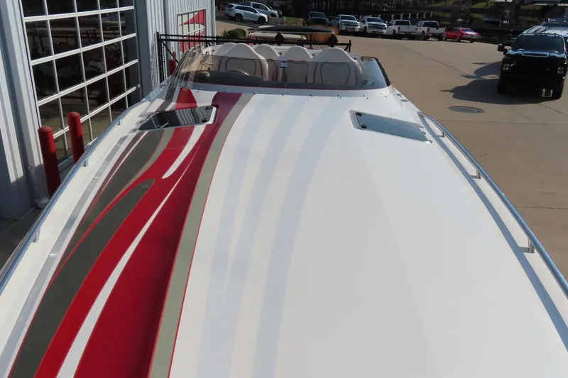 Slide: The Image of 2013 Nordic 39 Poker Run boat with sleek red and gray stripes, docked outdoors. - 11