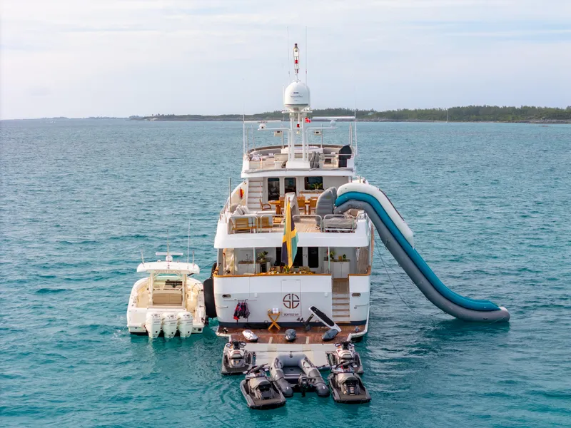 Slide: The Image of Christensen 1993 Semi Displacement yacht with slide, jet skis, and tender boat in open water. - 35