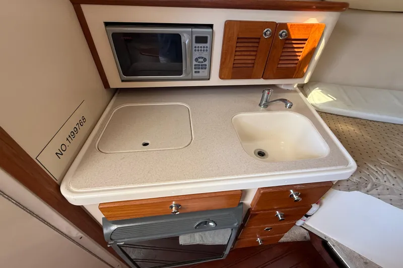 Slide: The Image of 2006 Pursuit 3370 Offshore boat kitchen with sink, microwave, and storage cabinets. - 12