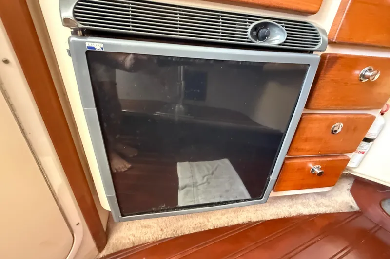 Slide: The Image of 2006 Pursuit 3370 Offshore interior with fridge and wooden drawers. - 13