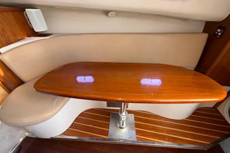 Slide: The Image of 2006 Pursuit 3370 Offshore cabin with wooden table and cushioned seating. - 17