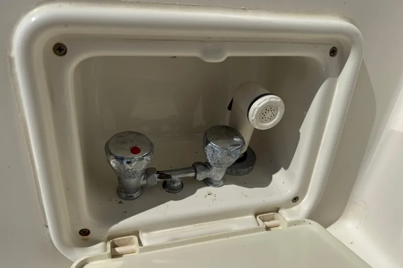 Slide: The Image of 2006 Pursuit 3370 Offshore boat faucet with dual controls in a white compartment. - 26