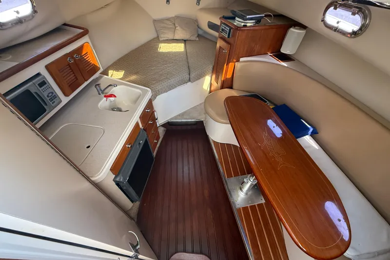 Slide: The Image of 2006 Pursuit 3370 Offshore cabin interior with kitchenette, bed, and seating area. - 32