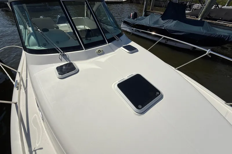 Slide: The Image of 2006 Pursuit 3370 Offshore boat deck with windshield and hatches, docked beside another vessel. - 7
