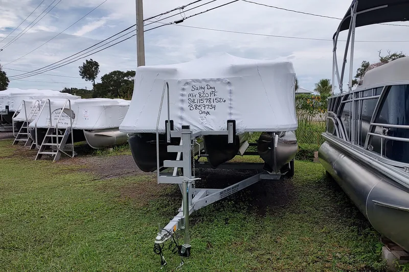 Slide: The Image of 2026 Sylvan Mirage 820 PARTY FISH boat covered, parked on grass with other boats. - 17