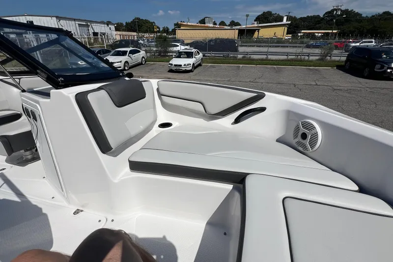 Slide: The Image of 2020 Yamaha Boats SX190 interior with cushioned seating and speaker, parked outdoors. - 19