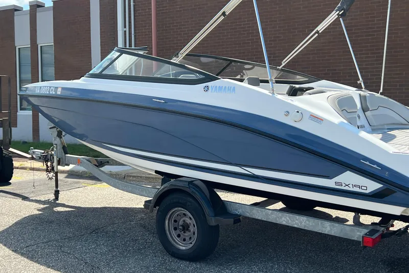 Slide: The Image of 2020 Yamaha SX190 boat on trailer, blue and white, parked near a brick building. - 3