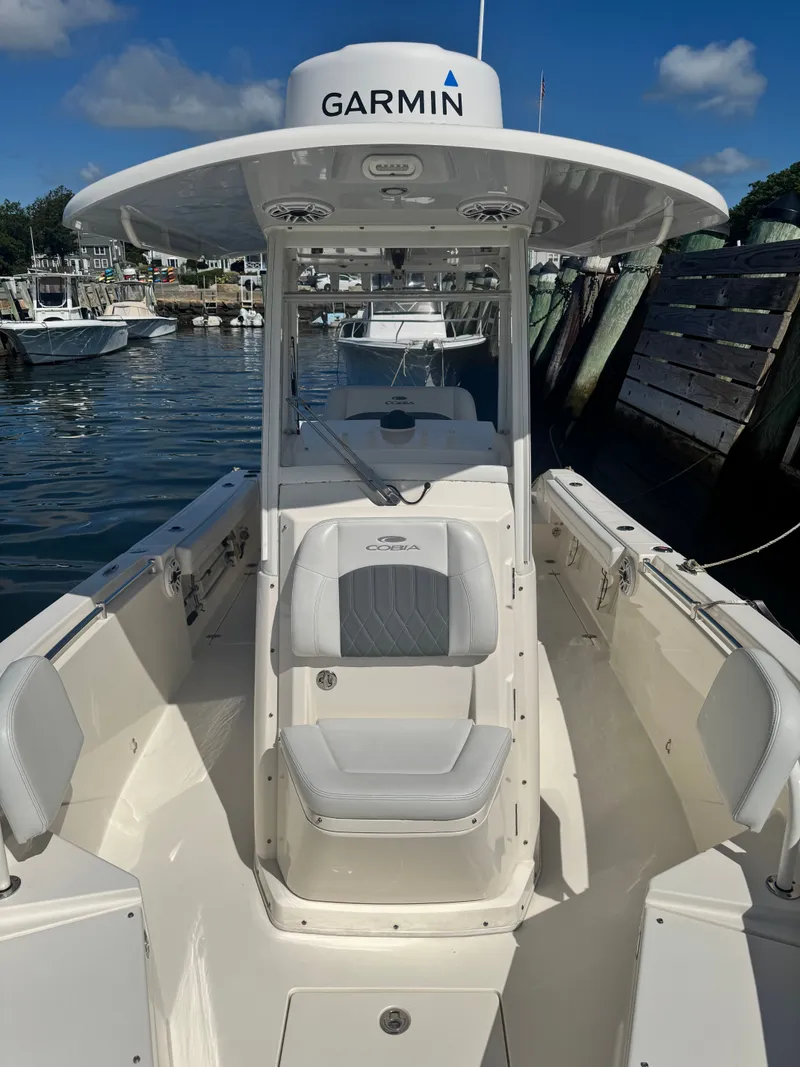 Slide: The Image of 2020 Cobia 240 Center Console boat docked, featuring Garmin equipment under a clear blue sky. - 11