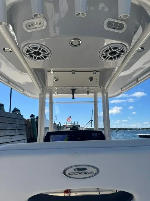 Slide: The Image of 2020 Cobia 240 Center Console boat interior with speakers, docked by the water. - 18