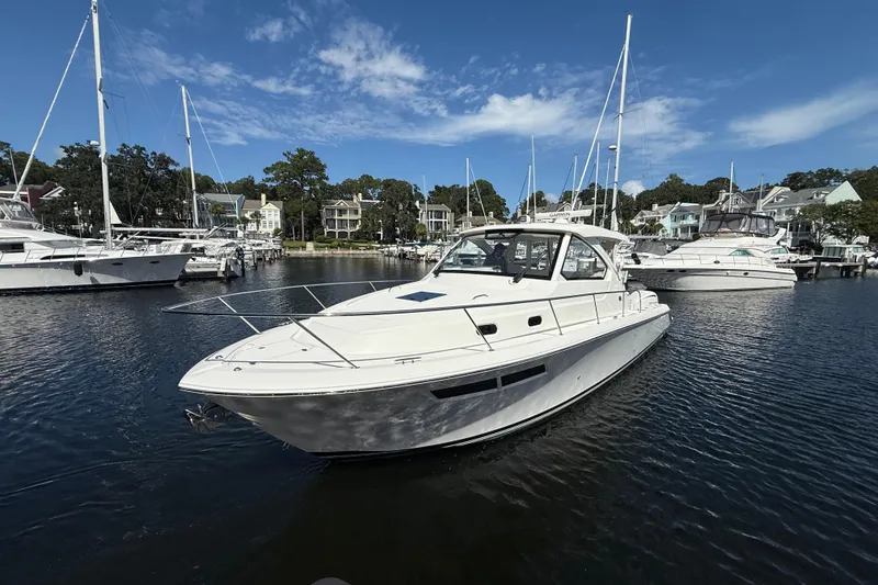 The Image of 2023 Pursuit OS 355 Offshore boat docked in a marina under a clear blue sky. - 1