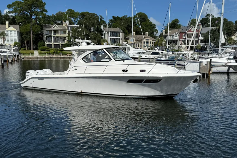 Slide: The Image of 2023 Pursuit OS 355 Offshore boat docked in a marina with waterfront homes. - 12