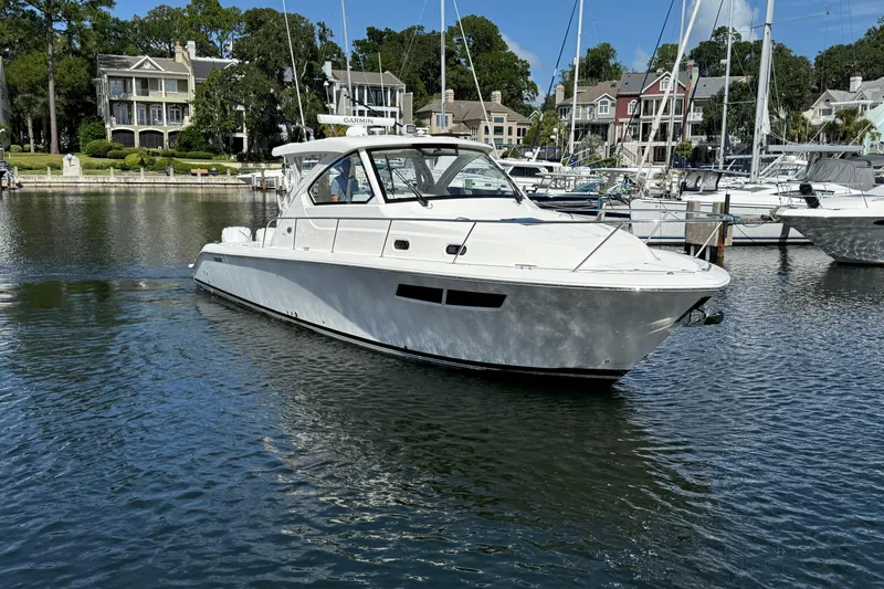 Slide: The Image of 2023 Pursuit OS 355 Offshore boat docked in a scenic marina setting. - 13