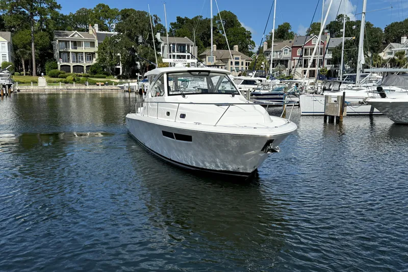 Slide: The Image of 2023 Pursuit OS 355 Offshore boat docked in a scenic marina. - 14