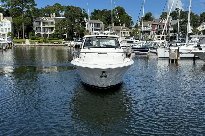 Slide: The Image of 2023 Pursuit OS 355 Offshore boat docked in a scenic marina with waterfront homes. - 15
