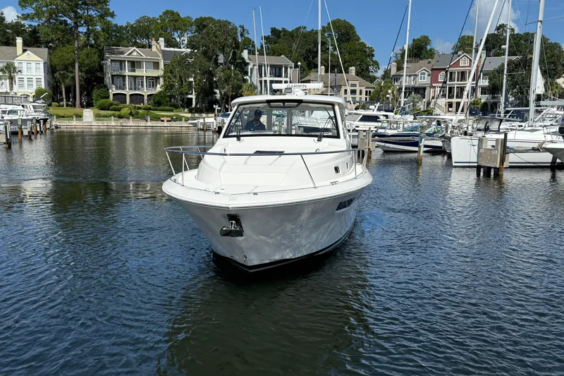 Slide: The Image of 2023 Pursuit OS 355 Offshore boat docked in a scenic marina setting. - 16