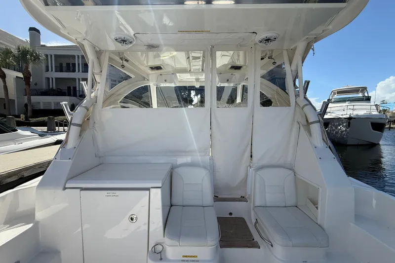 Slide: The Image of 2023 Pursuit OS 355 Offshore boat interior with white seating and storage, docked at marina. - 18