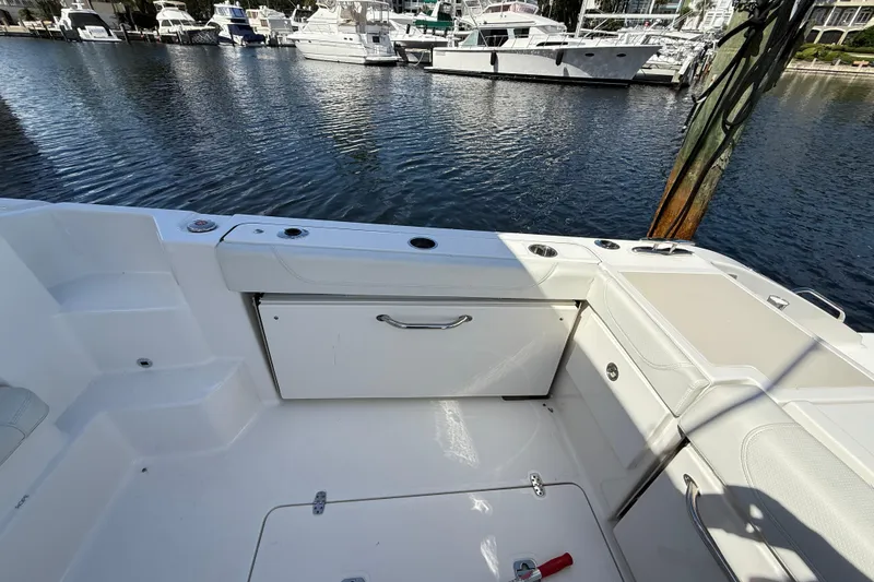 Slide: The Image of 2023 Pursuit OS 355 Offshore boat interior with storage and seating, docked at marina. - 21