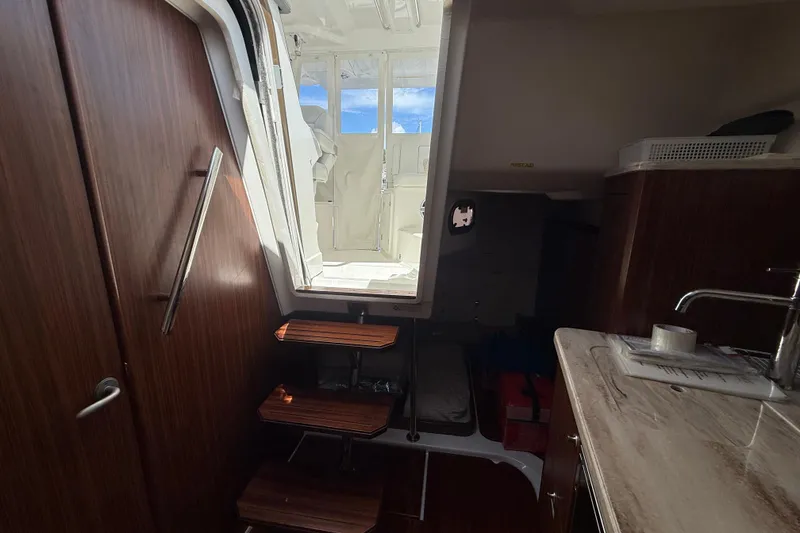 Slide: The Image of Interior view of 2023 Pursuit OS 355 Offshore boat, featuring wooden steps and a kitchenette. - 48