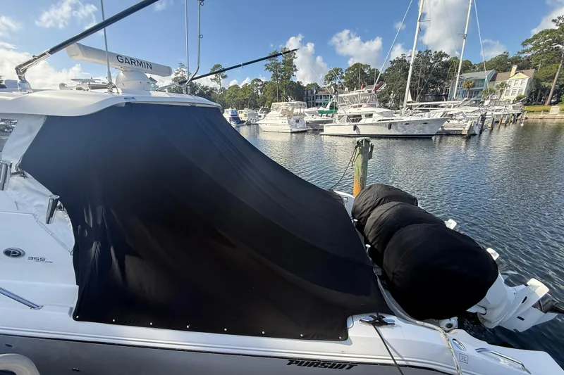 Slide: The Image of 2023 Pursuit OS 355 Offshore boat docked with black cover, marina background. - 56