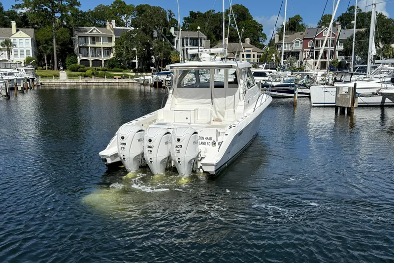Slide: The Image of 2023 Pursuit OS 355 Offshore boat docked in a marina with multiple engines. - 8