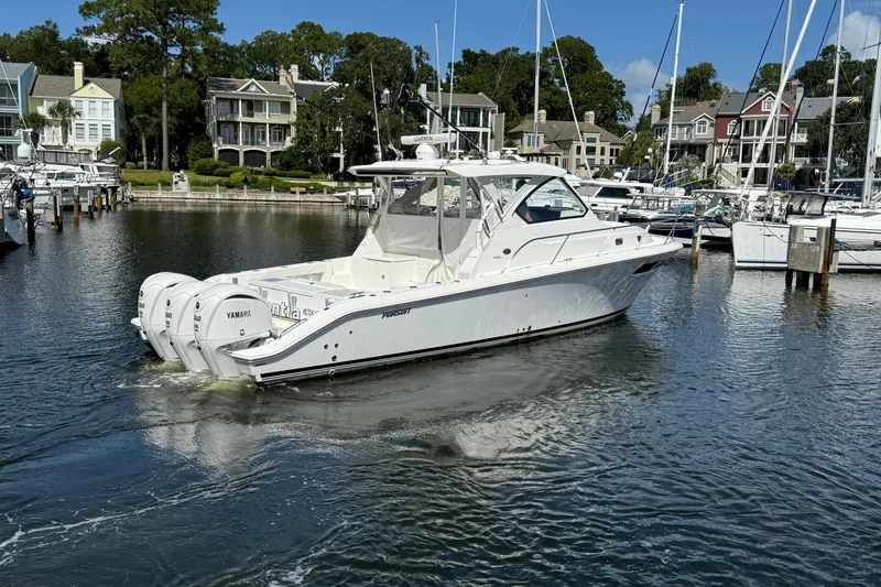 Slide: The Image of 2023 Pursuit OS 355 Offshore boat in marina, surrounded by waterfront homes and yachts. - 9