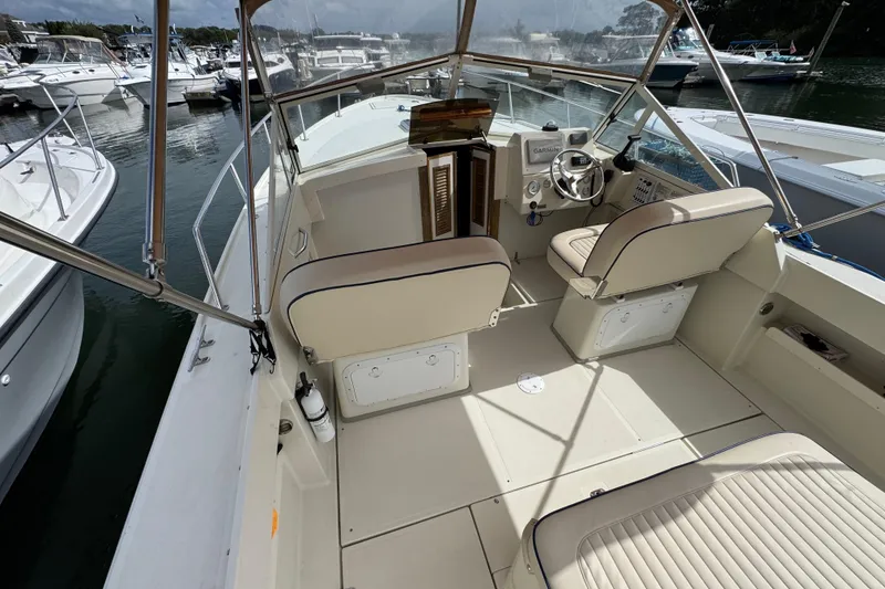 Slide: The Image of 2006 Limestone 26 boat interior with helm, seating, and marina view. - 10