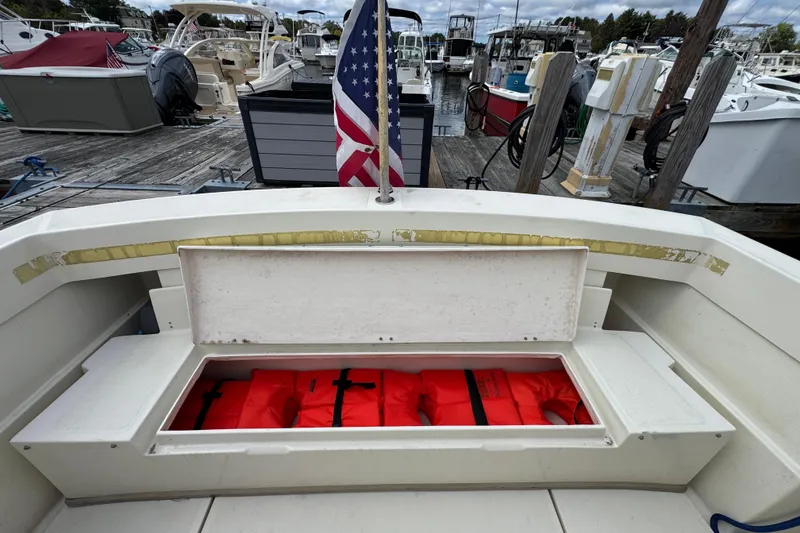 Slide: The Image of 2006 Limestone 26 boat with open storage compartment, red life jackets, and American flag at marina. - 11