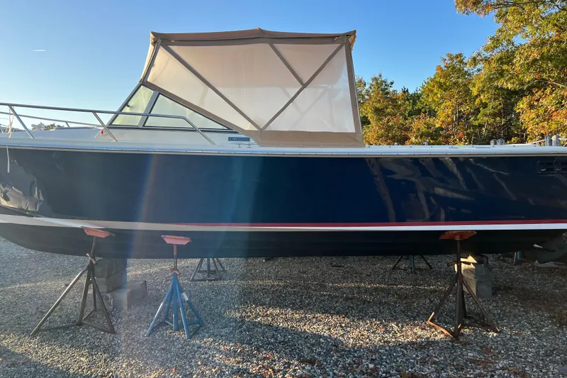 Slide: The Image of 2006 Limestone 26 boat on stands, blue hull, beige canopy, outdoor setting. - 2
