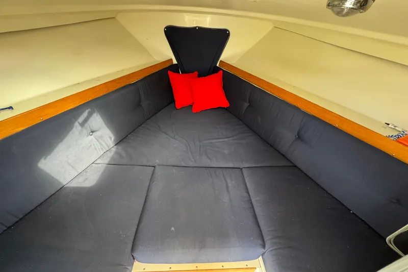 Slide: The Image of Cozy cabin interior of 2006 Limestone 26 boat with red cushions and dark seating. - 27