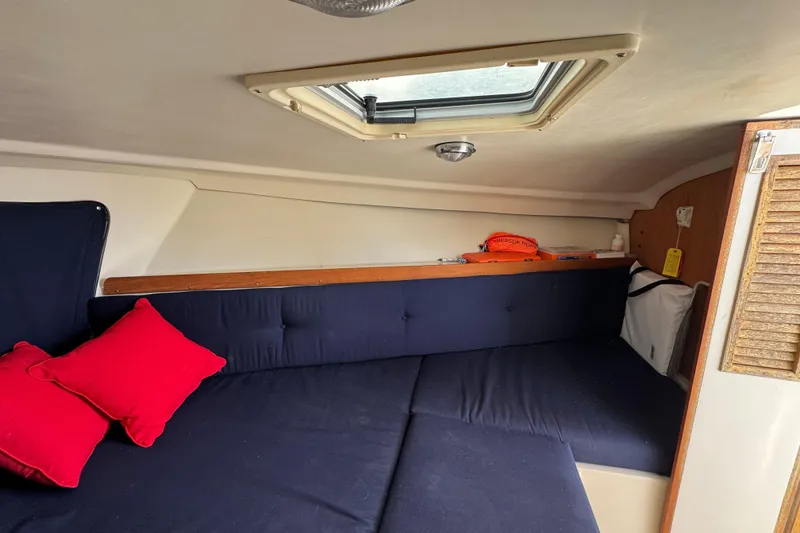 Slide: The Image of Interior cabin of a 2006 Limestone 26 boat with blue cushions and red pillows. - 29