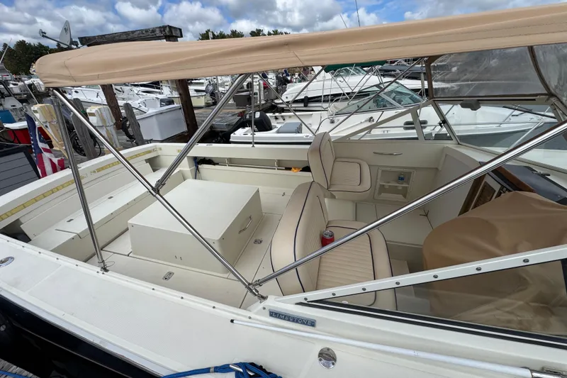 Slide: The Image of 2006 Limestone 26 boat with beige canopy and seating at a marina. - 4