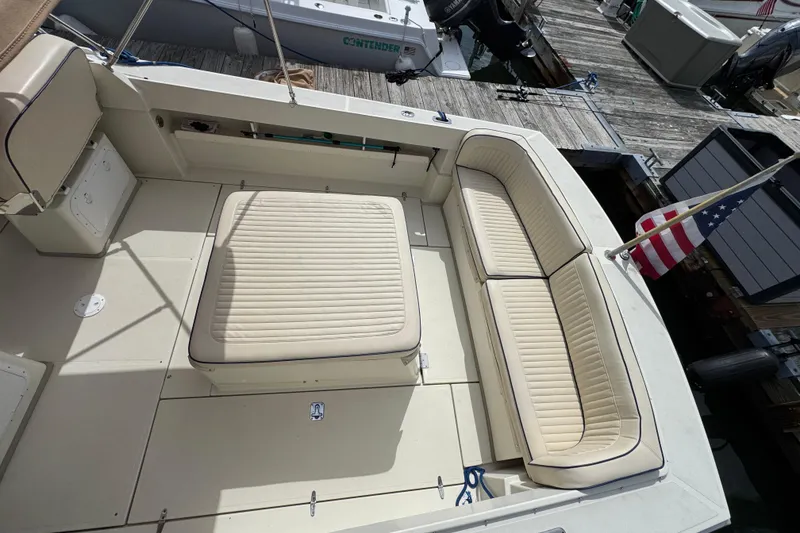 Slide: The Image of 2006 Limestone 26 boat interior with beige seating and American flag at dock. - 7
