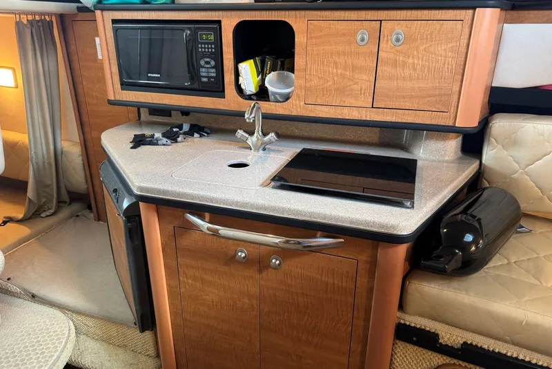 Slide: The Image of Compact kitchen area in a 2006 Sea Ray 260 Sundancer boat, featuring a sink and microwave. - 28