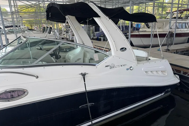 Slide: The Image of 2006 Sea Ray 260 Sundancer boat docked in a marina, featuring sleek design and black canopy. - 7