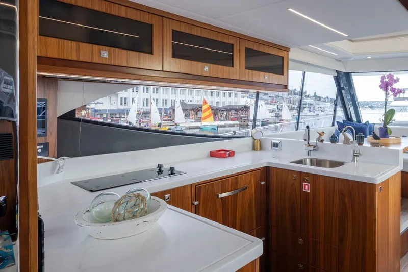 Slide: The Image of Luxurious 2023 Riviera 505 SUV yacht kitchen with modern wood cabinetry and marina view. - 4