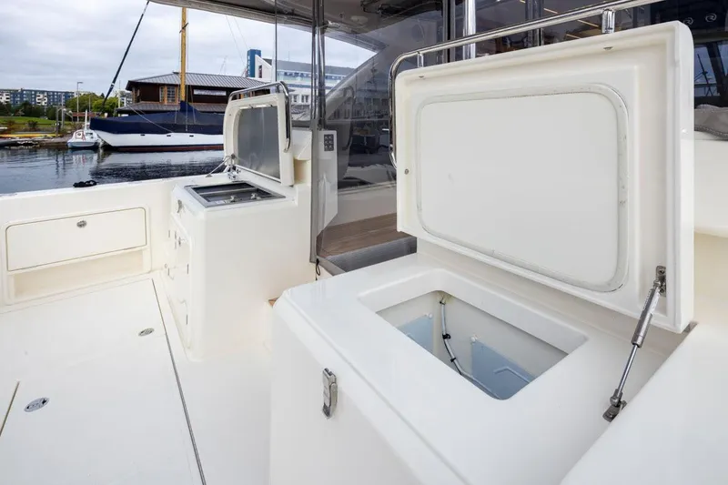 Slide: The Image of 2023 Riviera 505 SUV yacht deck with open storage compartments, docked in marina. - 43